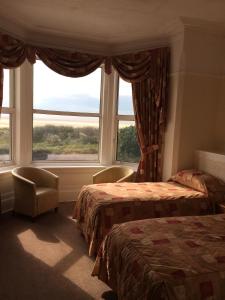 a bedroom with two beds and a large window at Monterey Beach Hotel in Lytham St Annes