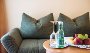 einen Tisch mit einer Flasche und eine Schale Obst auf einer Couch in der Unterkunft Vivea Hotel Bad Goisern in Bad Goisern