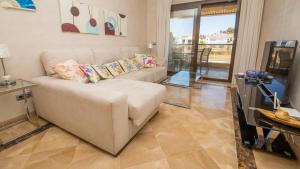 een woonkamer met een witte bank en een tafel bij Marina del Castillo 124 in Manilva