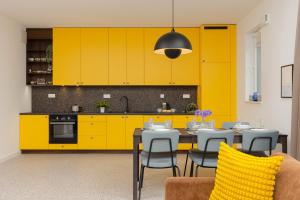 a kitchen with yellow cabinets and a table and chairs at Trendy & Spacious 3-room Apartament Warsaw Wilanów by Renters in Warsaw