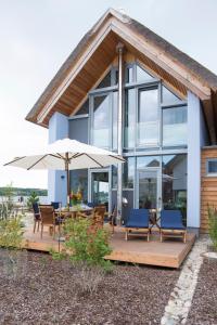 a house with a patio with chairs and an umbrella at Ostsee - Reetdachhaus Nr 5 "Beaufort" im Strand Resort in Heiligenhafen