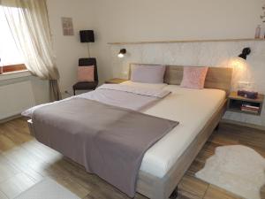 um quarto com uma grande cama branca com almofadas cor-de-rosa em Ferienwohnung Butscher em Isny im Allgäu