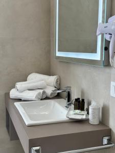 a bathroom with a sink and a mirror and towels at Hotel Villa Cedrino in Dorgali