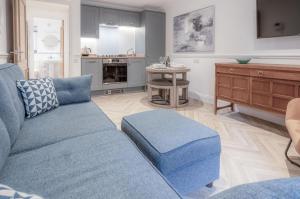 ein Wohnzimmer mit einem blauen Sofa und einer Küche in der Unterkunft The Cwtch - 2 Bedroom Apartment - Tenby in Tenby