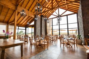 a dining room with tables and chairs and windows at Cerro Azul Hotel Fazenda in Capão Alto