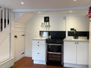Calbourne的住宿－Winkle Cottage，厨房配有白色橱柜和炉灶烤箱。