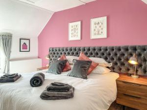 Calbourne的住宿－Winkle Cottage，卧室配有一张带粉红色墙壁的大床