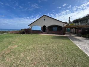 a house with a large yard in front of the ocean at La Vue in Port Shepstone