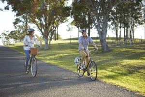 un hombre y una mujer montando bicicletas por un camino en Spicers Vineyards Estate en Pokolbin