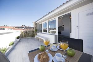 una mesa con 2 vasos de zumo de naranja en el balcón en Bolboreta Suites Boutique Apartments, en Santiago de Compostela