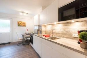 a kitchen with white cabinets and a sink and a table at Gerhart-Hauptmann-Strasse 1a Ferienhaus Alex in Kolpinsee