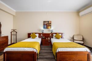 um quarto de hotel com duas camas com lençóis amarelos em Hotel Colmeia em Monte Real