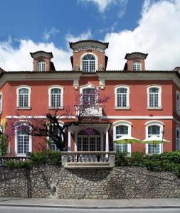 uma grande casa vermelha com uma cerca em frente em Hotel Do Parque, Boutique Hotel - Curia em Curia