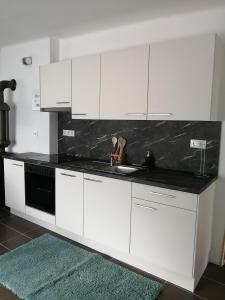 uma cozinha com armários brancos e um balcão preto em Apartment Wigo em Feldkirchen in Kärnten