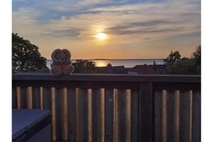 a teddy bear sitting on a fence watching the sunset at Ferienwohnung Hasenlodde in Loddin