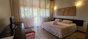 - une chambre avec un lit et une grande fenêtre dans l'établissement Águas de Santa Bárbara Resort Hotel, à Fábrica Santa Bárbara