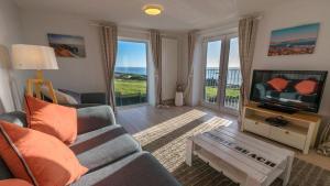 a living room with a couch and a television at Chesil Beach Lodge Burton Bradstock Dorset DT64RJ in Bridport