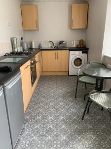 a kitchen with a sink and a table with chairs at The Greens Apartment in Farnworth