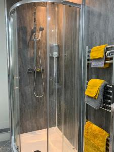 y baño con cabina de ducha y toallas amarillas. en The Greens Apartment en Farnworth