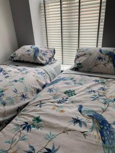 a bedroom with two beds with a bird patterned sheets at The Greens Apartment in Farnworth