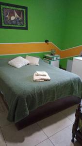 a green bedroom with a bed with two towels on it at La Josefina. in Maipú