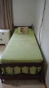 a bed with a green blanket and a pillow on it at La Josefina. in Maipú