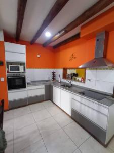 a large kitchen with orange walls and white cabinets at La Josefina. in Maipú