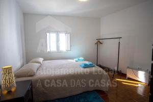 a white bedroom with a bed and a window at Casa Aconchego by AcasaDasCasas in Mafra