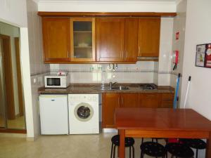 a kitchen with a washing machine and a microwave at Apartamentos Carolino in Monte Gordo