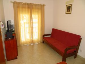 a living room with a red couch and a window at Apartamentos Carolino in Monte Gordo