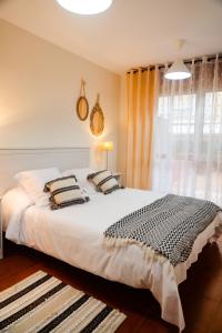 - une chambre avec un grand lit blanc et une fenêtre dans l'établissement Apartamentos Costa Norte, à San Vicente de la Barquera