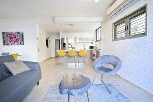 ein Wohnzimmer mit einem Sofa, Stühlen und einem Tisch in der Unterkunft Forever Young at Jean Jaures by HolyGuest in Tel Aviv