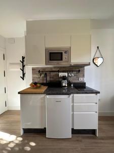 a kitchen with white cabinets and a microwave at Casa Secunda Romar in Córdoba