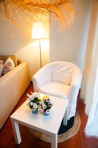 een woonkamer met een witte stoel en een tafel met bloemen bij Apartamentos Costa Norte in San Vicente de la Barquera