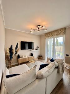 a living room with a white couch and a tv at Silesia Apartments Ustron H125 in Ustroń