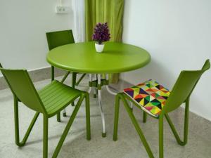 a green table with two chairs and a vase with flowers at Purabi's Nest in Tezpur