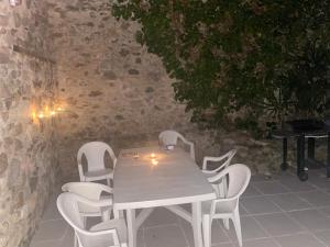 une table et des chaises blanches avec des lumières allumées dans l'établissement Maison les Ramparts, à Villefranche-de-Conflent