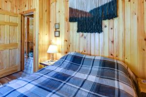a bedroom with a bed in a wooden wall at Riverfront Rumney Vacation Rental with Fire Pit! in Rumney