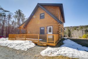 a log cabin with a porch in the snow at Riverfront Rumney Vacation Rental with Fire Pit! in Rumney