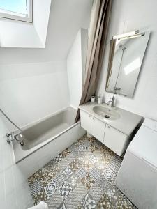 La salle de bains est pourvue d'un lavabo, d'une baignoire et d'un miroir. dans l'établissement T2 neuf Top Cocooning – Terrasse – Face à la mer, à Ploemeur