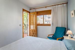 1 dormitorio con cama, silla azul y ventana en Casa en la playa con piscinas E, en Puerto Marino 22 fotos más