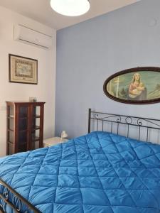 a bedroom with a blue bed and a painting on the wall at La Casuccia in Siracusa