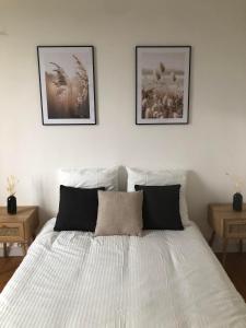 a bedroom with a white bed with two pictures on the wall at Chez julie in Caen