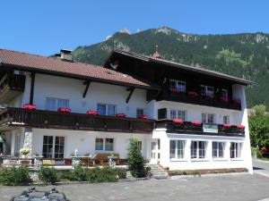 ein großes weißes Gebäude mit einem Berg im Hintergrund in der Unterkunft Alpenhof Wängle in Reutte