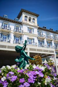 a statue in front of a building with flowers at Grand Hotel du Lac - Relais & Châteaux in Vevey