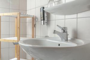 a bathroom with a white sink and a shelf at Hotel Kruse Zum Hollotal in Neuenkirchen-Vörden