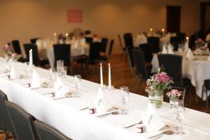 una mesa larga con mantel blanco y flores. en Hotel Kruse Zum Hollotal en Neuenkirchen-Vörden