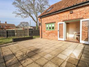 a brick house with a patio in front of it at The Old Cartshed in Lowestoft