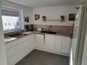 uma cozinha com armários brancos, um lavatório e uma janela em Holiday Home Doris em Bad Goisern