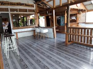 a restaurant with a wooden floor and a bar with stools at Mentawai Bagus Local Homestay in Tua Pejat